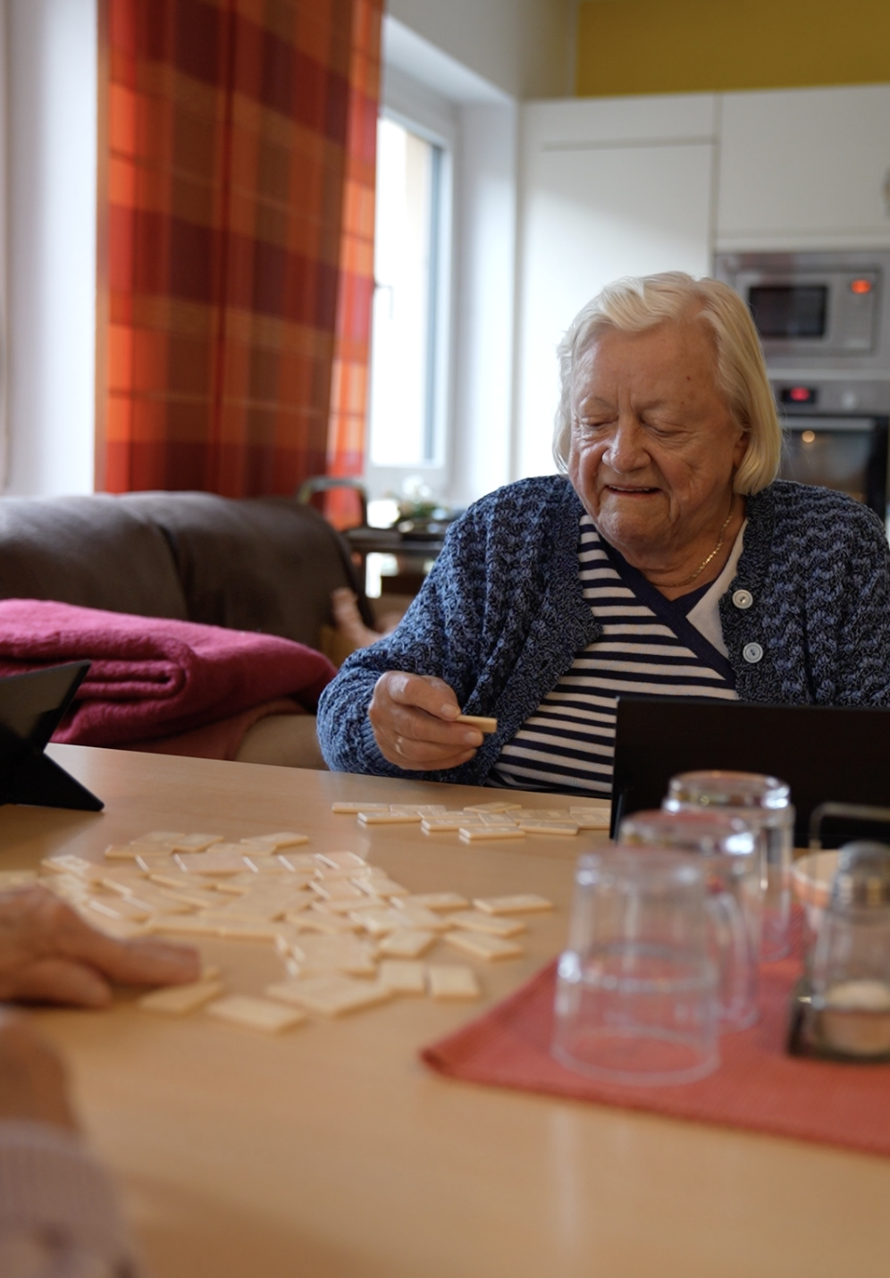 Bewohnerin beim Spielen am Tisch in der Hausgemeinschaft